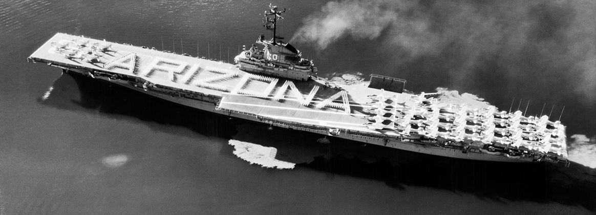 USS Bennington (CVA-20) passes the wreck of USS Arizona (BB-39) in Pearl Harbor, Hawaii, on Memorial Day, May 31, 1958.